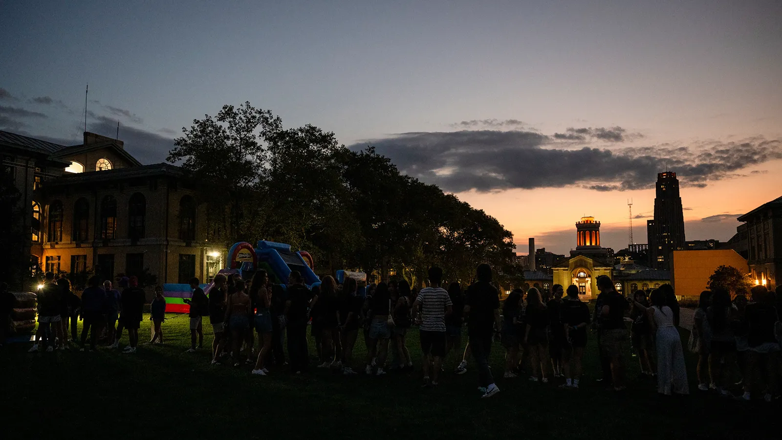 Students outside on campus with the sun setting in the background