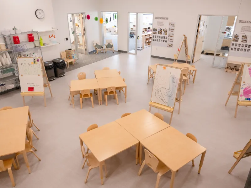 Empty Cyert classroom space with white walls and light wooden tables.