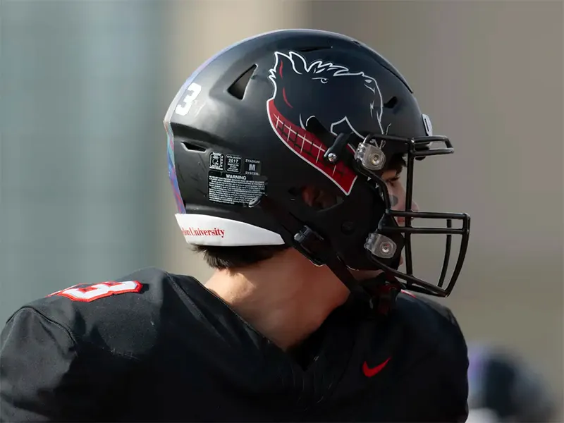Student football player wearing a black helmet with Scotty, the Carnegie Mellon University mascot.