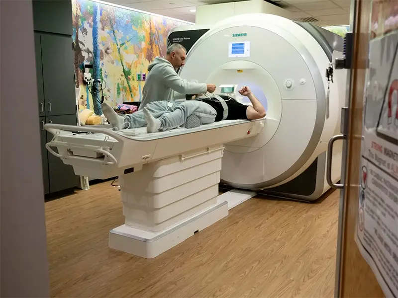 A person on a table being hooked up to be scanned in an MRI machine.