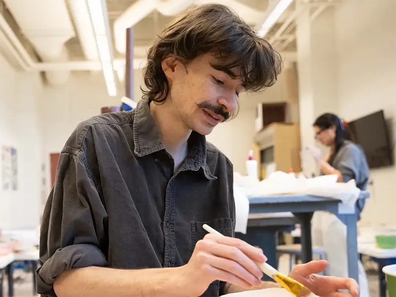 A student glazing a bowl in the School of Art ceramic studio.