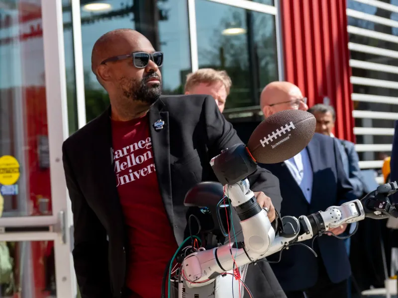 Man shows off a robot that can throw a football. 