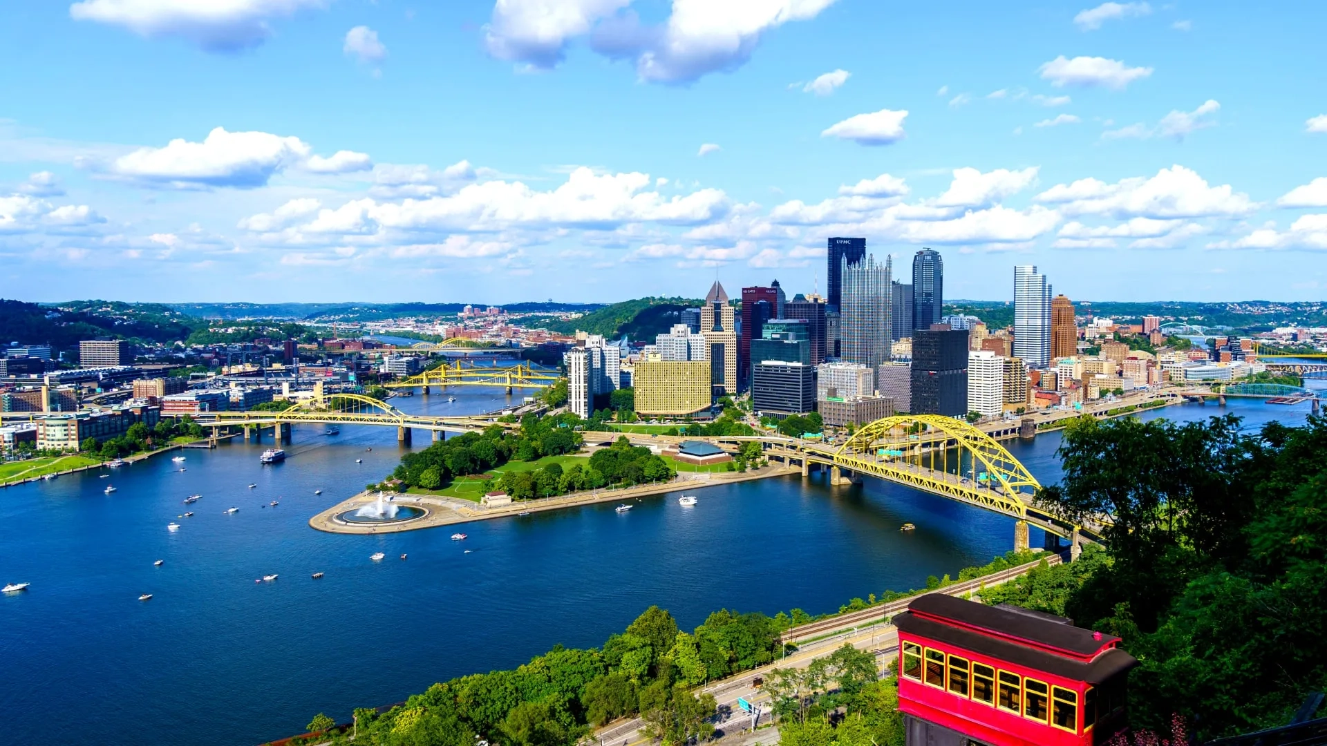 Scenic aerial view of the Pittsburgh, PA skyline on a sunny day showing multiple rivers and the iconic yellow bridges
