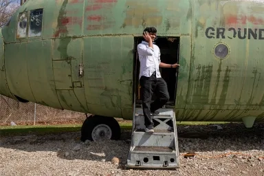Photo of a CMU student wearing a headset stepping out of an airplane.