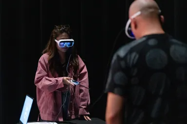Two people wearing virtual reality glasses interacting with a controller